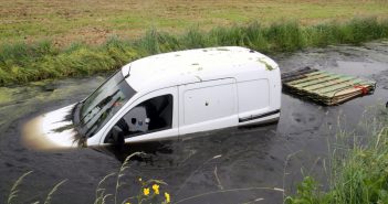 Man met bedrijfsauto en kar te water in Nieuw-Lekkerland